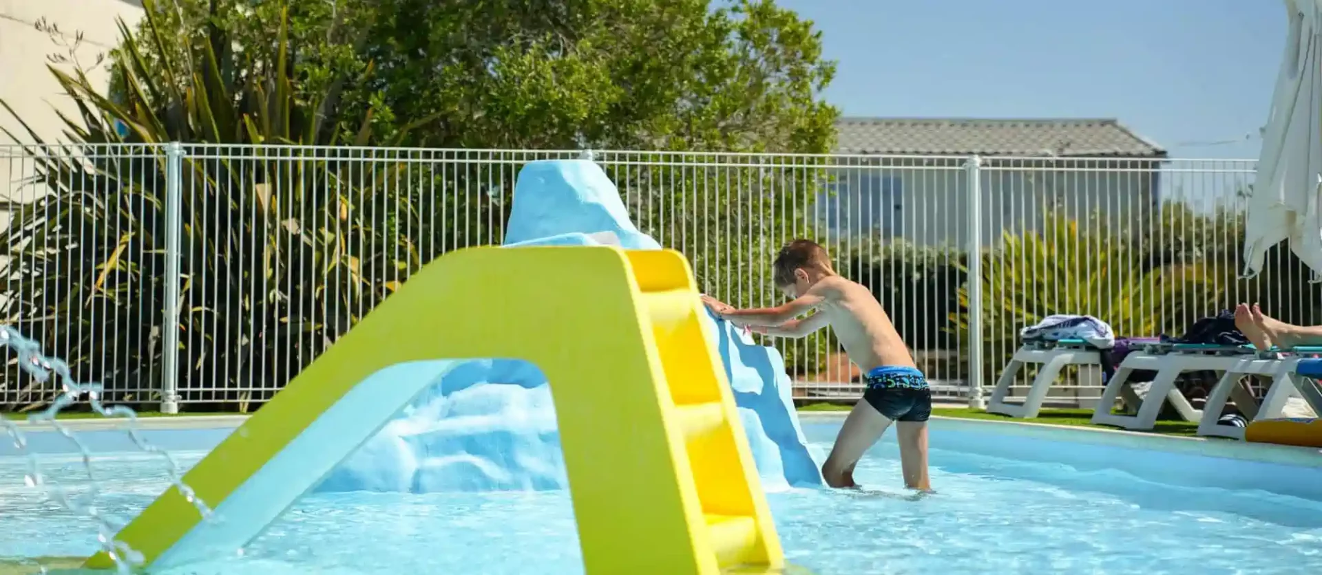 Enfant jouant sur le toboggan de la pataugeoire au camping de Brem-sur-Mer